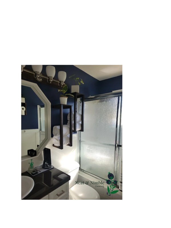 Modern bathroom with dark blue walls, floating shelves, white towels, and frosted glass shower.