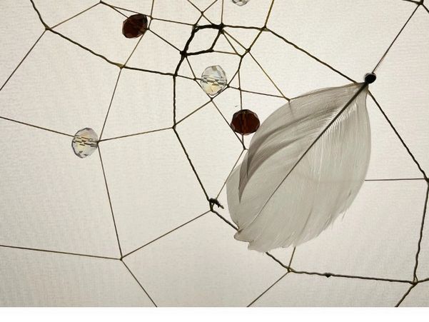 Close-up of a delicate dreamcatcher with a white feather and beads.
