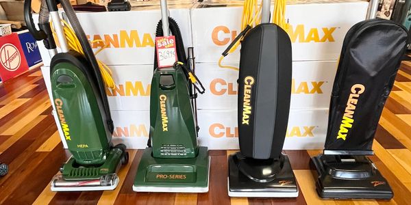 Four CleanMax upright vacuum cleaners displayed in a store with wooden flooring.