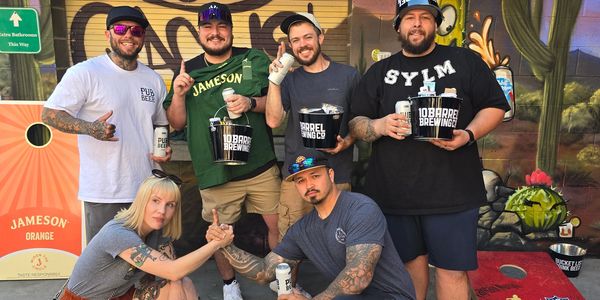 a group of friends posing with prizes from a cornhole event
