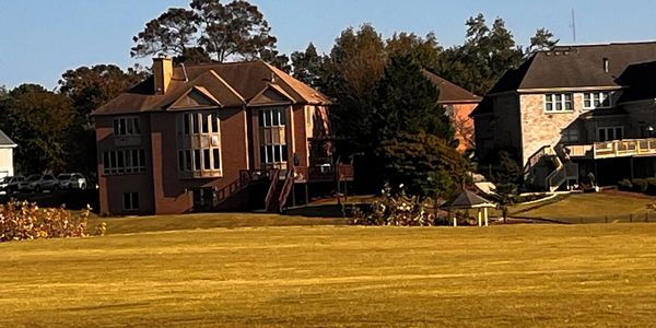 Front view of Masters Lake Estate, a distinguished lakefront executive residence in Metro Atlanta, featuring a grand architectural design and a wide open grassy lawn.