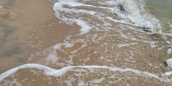 Frothy white waves along a sandy beach shore. 