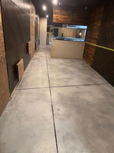 Narrow hallway with polished concrete floor and wood-paneled walls.