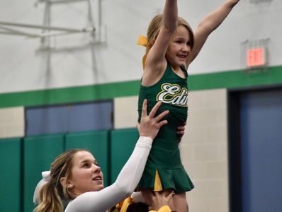 Young cheerleader lifted by teammate during practice.