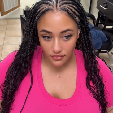 Woman with intricate cornrow braids wearing a bright pink top.