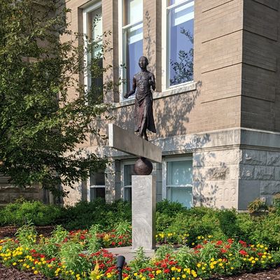 Photo of "Balance" statue portraying a person walking on a beam balanced on a sphere above flower be