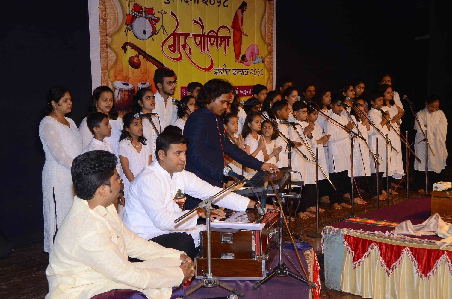 A group of people performing traditional Indian music and singing on stage.