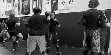 People practicing martial arts in a gym with flags on the wall.