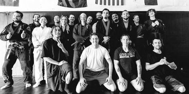 Group of martial artists posing together in a training gym.