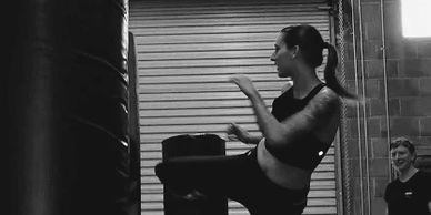 Woman practicing kickboxing with a punching bag in a gym.