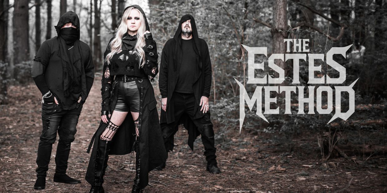 Three members of The Estes Method band in dark gothic attire in a forest.
