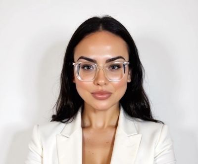 Woman with glasses wearing a white blazer.