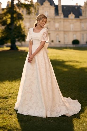 Woman in elegant ivory lace gown outdoors.