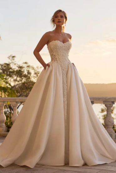 Woman in elegant strapless ivory gown outdoors.