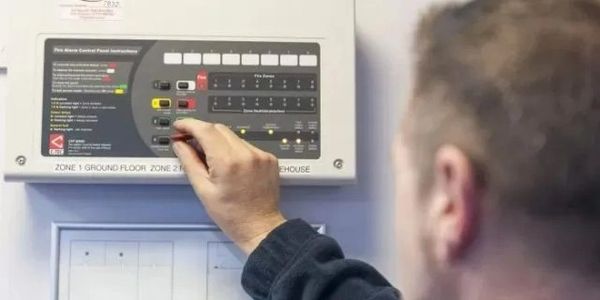 Person adjusting settings on a fire alarm control panel.