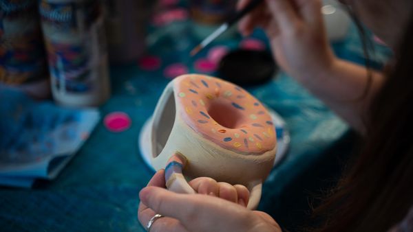 Premade ceramic being painted by artist with underglaze. Paint your own pottery. 