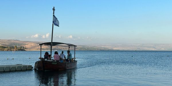 Boat with people on a calm lake under a clear sky.
