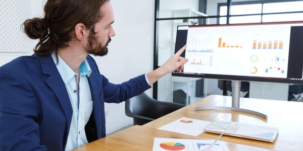 Man in a suit analyzing financial charts on a computer screen.