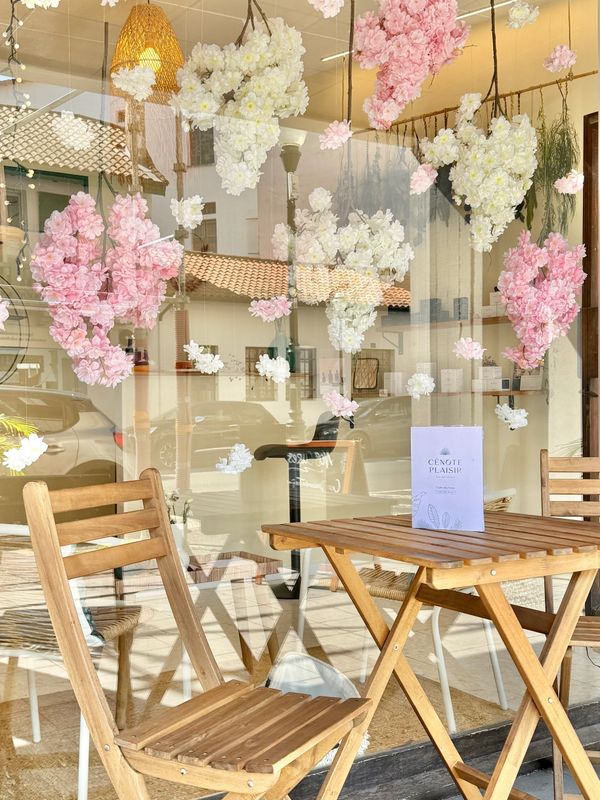 Cozy outdoor cafe seating with wooden chairs and floral window decorations.