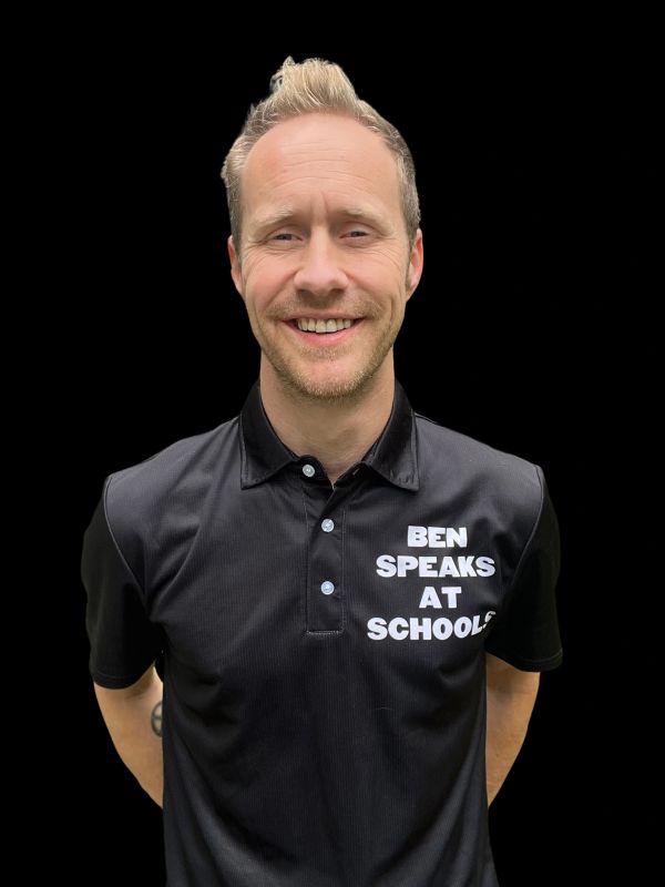 Smiling man wearing a black polo shirt that reads 'Ben Speaks at Schools'.