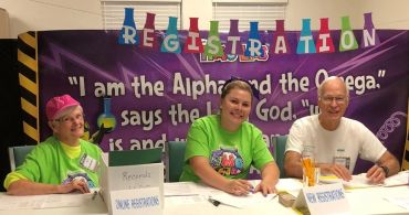 Three volunteers at a registration desk.