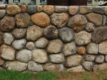 Rounded stone retaining wall in a garden setting.