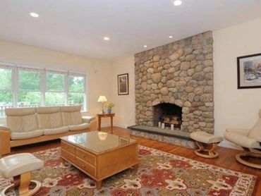 Stone wall fireplace in a cozy living room with a coffee table and sofa.
