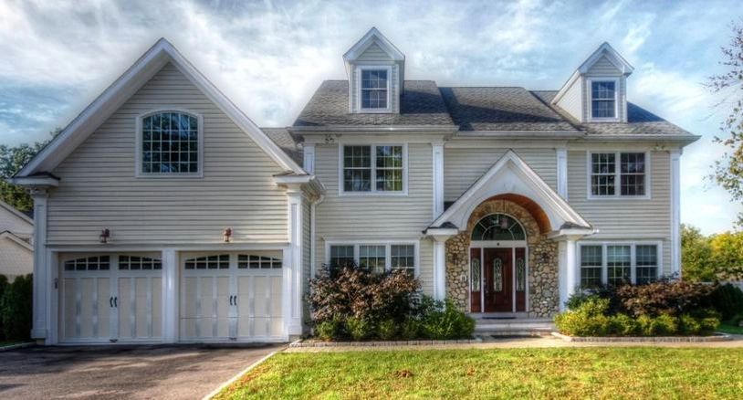 Front exterior of a large, light-colored house with a two-car garage and a stone-accented entryway.
