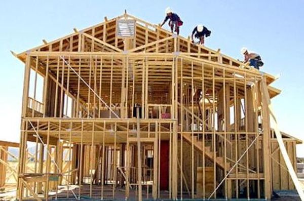 Three construction workers framing a house roof.