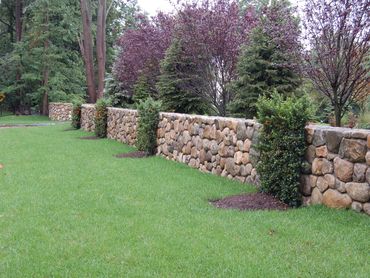 Low stone retaining wall on a grassy slope.
