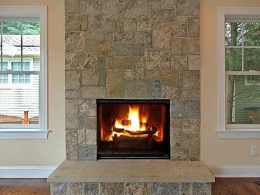 Tiled stone fireplace with a hearth and mantel in a bright living room.
