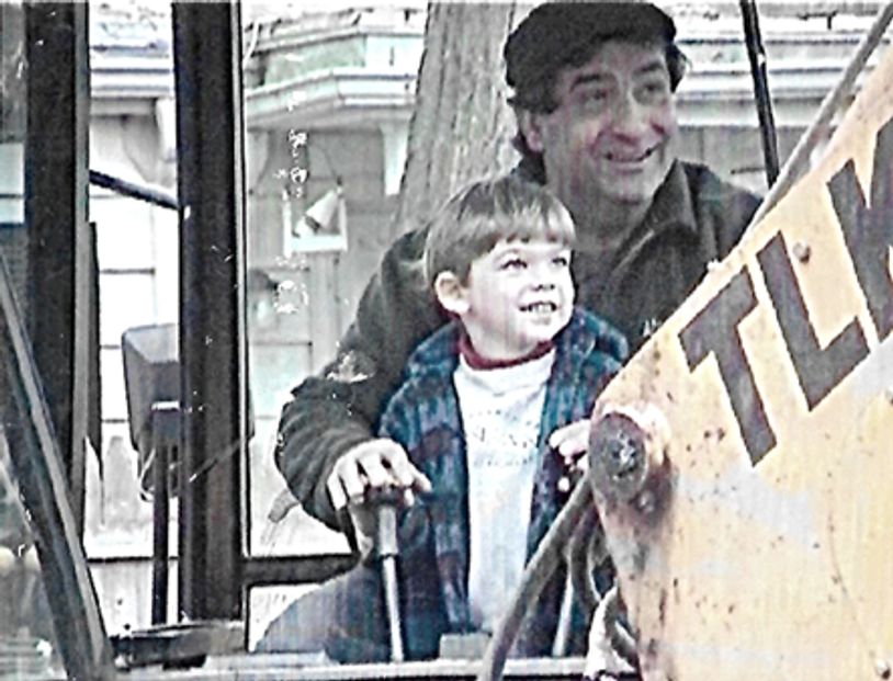Man and smiling child sitting in an excavator.
