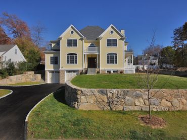 Large stone wall foundation beneath a light-colored house.
