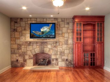 Stone fireplace with a built-in TV and red wooden cabinets.
