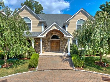 Grand home exterior featuring stone siding and an arched entrance.

