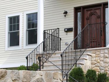 Stone steps with a black railing leading to a dark wooden door.

