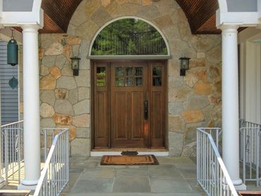 Arched stone portico around a wooden entry door.

