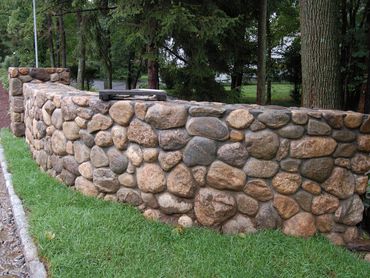 Short, rustic rock wall in a front yard landscape.
