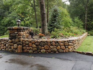Stone wall in a sunny, landscaped yard.