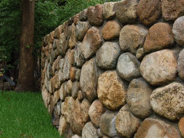 Stone wall texture with surrounding greenery.
