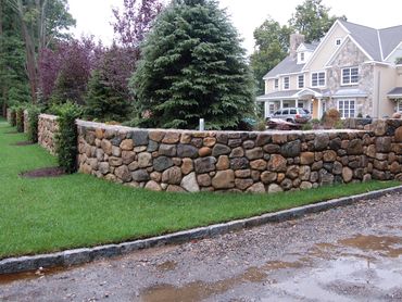 Landscaping with a tiered stone wall and mature trees.

