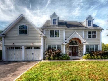 Large, upscale house with stone accents, long driveway, and well-kept lawn.
