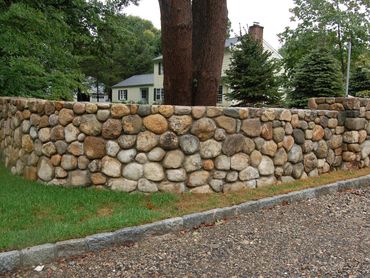 Natural rock border next to a lawn and trees.
