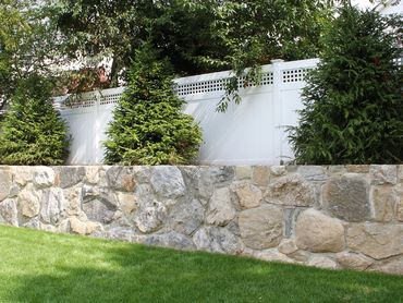 Stone work and landscape design in front of a large home.
