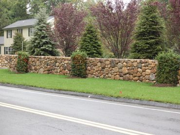 Curved stone wall by a driveway entrance.
