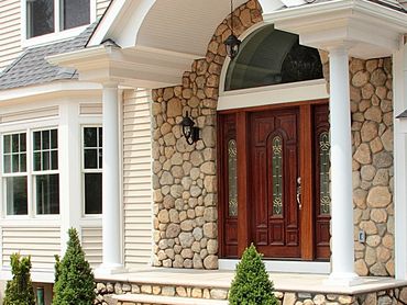 Home entrance with white siding, stone veneer, and a red-brown door.
