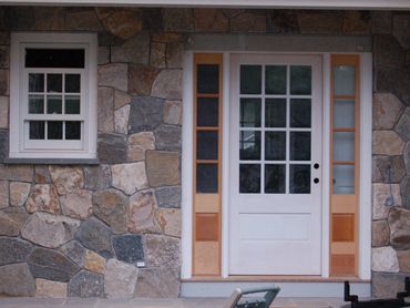 White panel door with glass in a stone and siding exterior wall.
