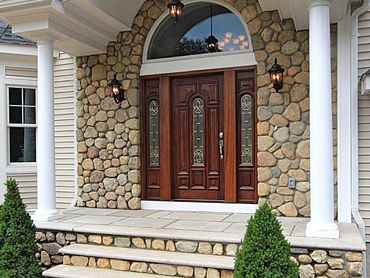 Home entrance with stone veneer and an arched wooden front door.
