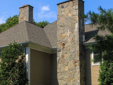 Stone chimney detail against the roofline and surrounding trees.
