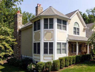 Front view of a classic house with a central stone chimney and landscaping.
